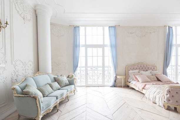 intérieur lumineux et luxueux dans le style baroque. Une pièce spacieuse avec un mobilier beau et chic, une cheminée et des fleurs. Plantes en stuc sur les murs et parquet en bois clair.